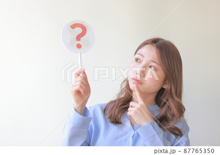 はてなのプレートを持ち何でだろうと考える女性3 87765350