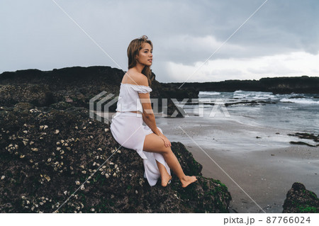 Sensual woman sitting on stone cliff Sensual woman sitting on stone cliff 87766024