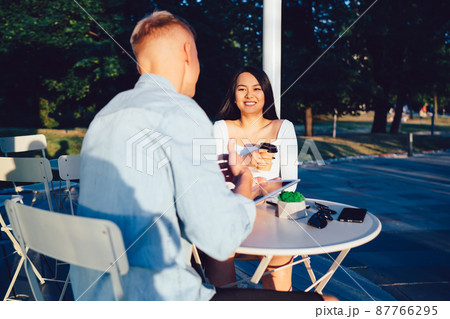 Cheerful diverse couple talking in outdoor cafe Cheerful diverse couple talking in outdoor cafe 87766295