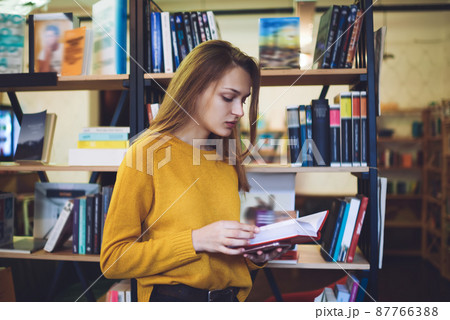 Young woman reading book in library 87766388