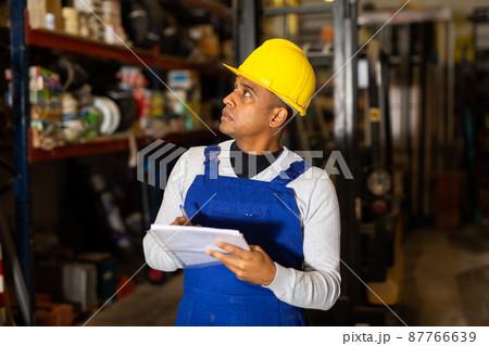 Warehouse manager calculates the quantity of goods and writes it down in notebook 87766639
