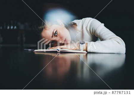 Student lying on table and looking tired doing homework 87767131