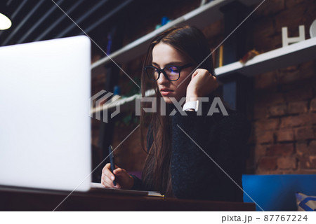 Serious woman taking notes while studying Serious woman taking notes while studying 87767224
