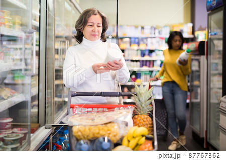 Elderly woman choosing dairy products in supermarket Elderly woman choosing dairy products in supermarket 87767362