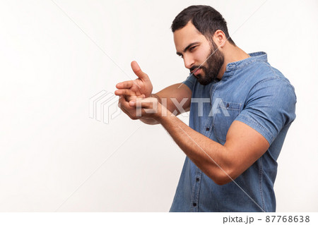 Assertive dangerous man with beard pointing fingers at target imitating weapon making shot, terrorism. Indoor studio shot isolated on white background Assertive dangerous man with beard pointing fingers at target imitating weapon making shot, terrorism. Indoor studio shot isolated on white background 87768638