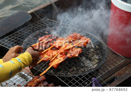 Chicken clamping bamboo grilling on grate. 87768692