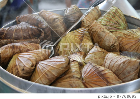 The rice wrapped in lotus leaf are steaming. 87768695