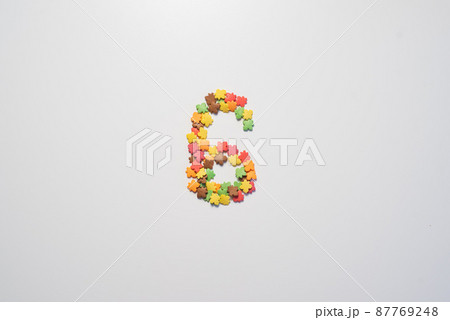 Number six from sweet pastry topping in the form of colorful foliage on a white background. Number six from sweet pastry topping in the form of colorful foliage on a white background. 87769248