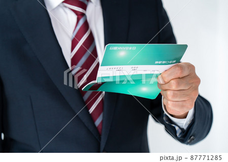 通帳を見て悩むビジネスマン　手元 87771285