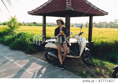 Cheerful Caucasian blogger using cellphone gadget and vintage transport in Indonesia 87771827