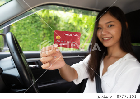 Happy young Asian woman driving car and holding credit card on hand 87773101