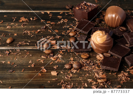Chocolate pieces and candy on dark wooden table. Chocolate pieces and candy on dark wooden table. 87773337