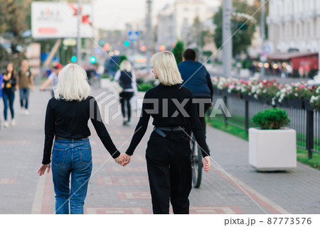 Two young females walking smiling embracing and kissing outdoor in the city Two young females walking smiling embracing and kissing outdoor in the city 87773576