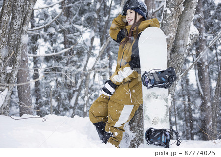 雪の降るスキー場に立つスノボ女子の写真素材