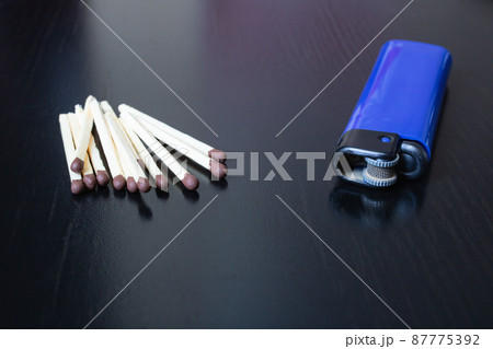 Pile of matches and lighter on black wooden table 87775392