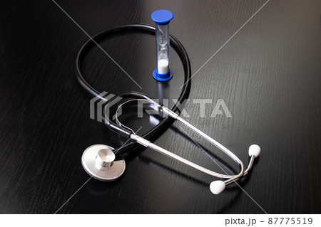Stethoscope and hourglass on a wooden table 87775519