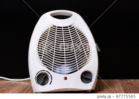 White fan heater on a wooden floor 87775565