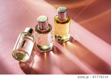 Glass bottle cosmetics with aroma oil for beauty or skin care on pink background, natural sun light and shades. Glass bottle cosmetics with aroma oil for beauty or skin care on pink background, natural sun light and shades. 87778210