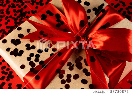 A large gift box with red ribbons and confetti on a red background .The concept of a holiday, invitations, sales, invitations to a wedding ,birthday. A large gift box with red ribbons and confetti on a red background .The concept of a holiday, invitations, sales, invitations to a wedding ,birthday. 87780872