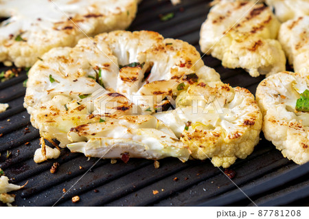 Cooking cauliflower steak with herbs and spices. Healthy vegetarian snack, close-up. Cooking cauliflower steak with herbs and spices. Healthy vegetarian snack, close-up. 87781208