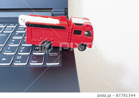 黒いパソコンのキーボードの上で単独事故を起こして脱輪している消防車 87781344