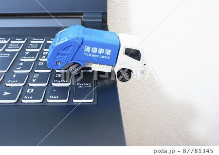 黒いパソコンのキーボードの上で単独事故を起こして脱輪しているごみ収集車 87781345