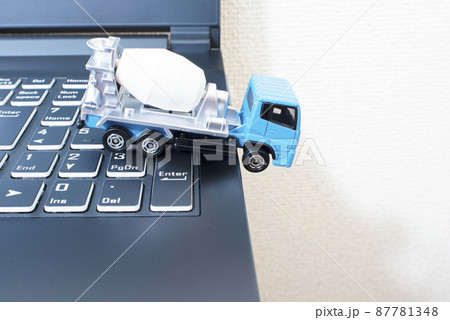 黒いパソコンのキーボードの上で単独事故を起こして脱輪しているミキサー車 87781348