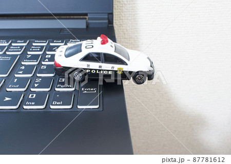 黒いパソコンのキーボードの上で単独事故を起こして脱輪している日本のパトカー 87781612