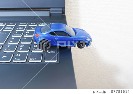 黒いパソコンのキーボードの上で単独事故を起こして脱輪している青色のスポーツカー 87781614