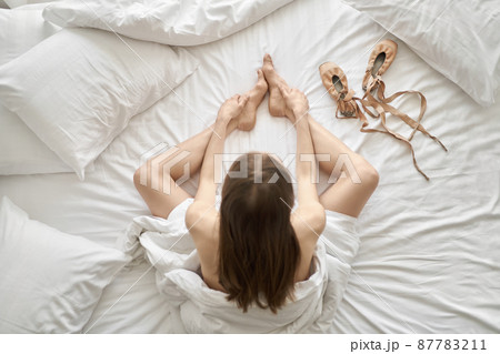 Woman wrapped in blanket posing on light bed 87783211