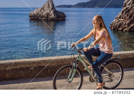 Woman tourist on a bicycle explores Budva in Montenegro. Cycling in Montenegro concept Woman tourist on a bicycle explores Budva in Montenegro. Cycling in Montenegro concept 87784202