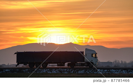 Semi-truck with cargo trailer driving on highway hauling goods in evening. Delivery transportation and logistics concept 87785466