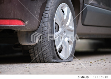 Car with punctured flat tire parked on roadside Car with punctured flat tire parked on roadside 87786046
