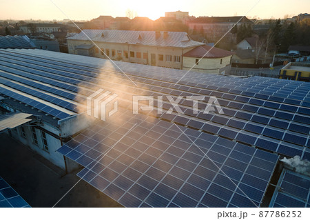 Aerial view of blue photovoltaic solar panels mounted on industrial building roof for producing green ecological electricity. Production of sustainable energy concept 87786252