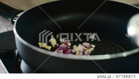 The cook woman hand puts the chopped onion on a hot pan with sunflower oil. The cook woman hand puts the chopped onion on a hot pan with sunflower oil. 87786873