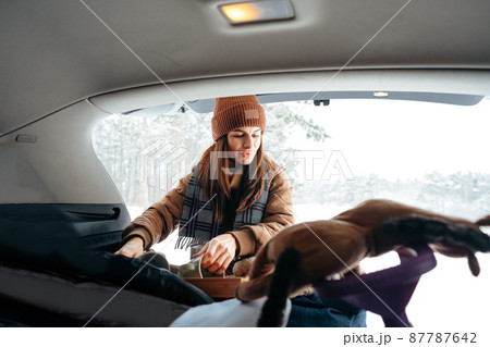 Young woman taking luggage out of car on winter trip Young woman taking luggage out of car on winter trip 87787642