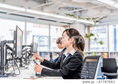 フリーアドレスのオフィスで仕事をする女性 87787661