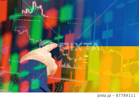 Ukraine downtrend of the economy in a world crisis. Man hand shows on the decreasing candle stick graph chart in the stock market with the flag on the background, March 2022, San Francisco, USA 87789111