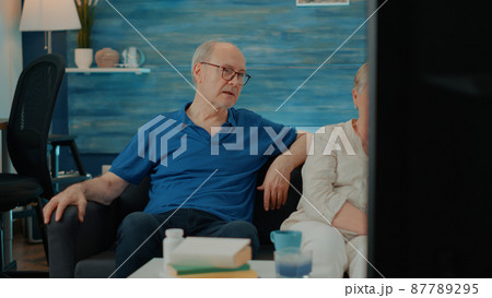 Married people watching movie on television in living room 87789295