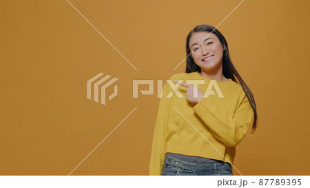 Positive adult pointing at left side of studio in front of camera 87789395