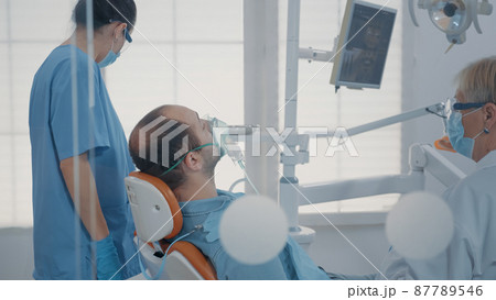 Dental assistant using oxygen mask to do anesthesia on patient Dental assistant using oxygen mask to do anesthesia on patient 87789546