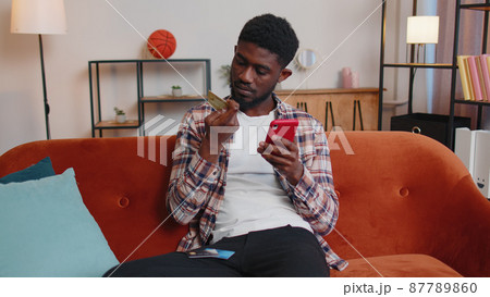 Man sitting at home using credit bank card and smartphone while transferring money online shopping 87789860