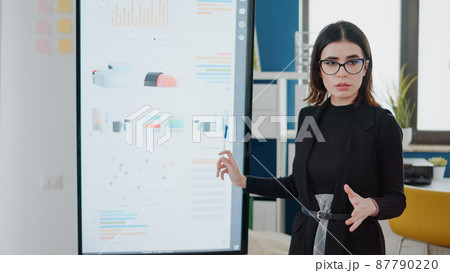Businesswoman pointing at television with data charts 87790220