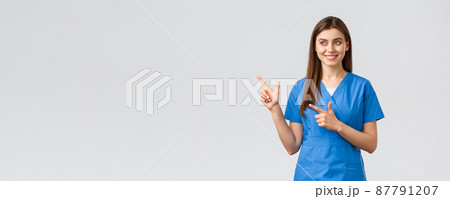 Healthcare workers, prevent virus, insurance and medicine concept. Smiling pretty nurse or doctor in blue scrubs, pointing fingers left and looking at baner with pleased grin, grey background 87791207