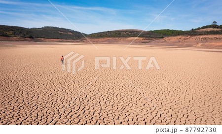 Silhouette of a man on a sandy cracked empty not fertile land during a drought. The concept of ecological catastrophe on the planet. 87792730