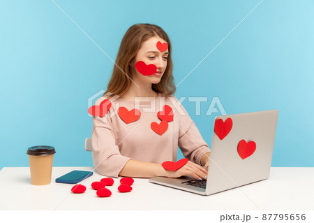 Amazing positive woman with kind expression sitting all covered with sticker love hearts and typing on laptop, dating chatting online, romantic relationship on internet. indoor studio shot, isolated Amazing positive woman with kind expression sitting all covered with sticker love hearts and typing on laptop, dating chatting online, romantic relationship on internet. indoor studio shot, isolated 87795656