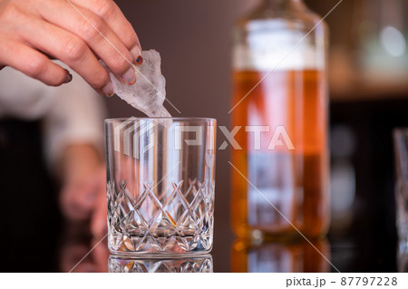 グラスに氷を入れる手元　BAR 87797228