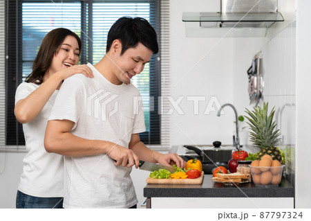 couple cutting vegetables for preparing healthy food in the kitchen at home. woman making massage to man couple cutting vegetables for preparing healthy food in the kitchen at home. woman making massage to man 87797324