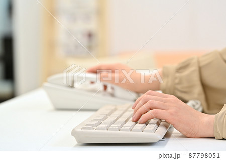 キーボードを打ちながら受話器に手を伸ばす女性の手元 キーボードを打ちながら受話器に手を伸ばす女性の手元 87798051
