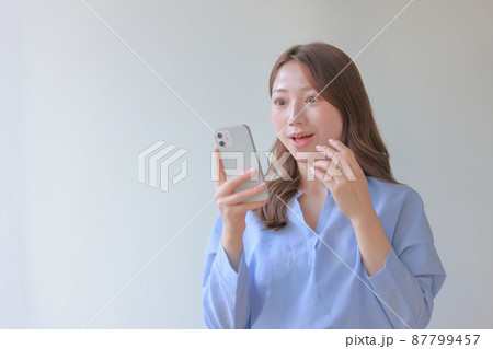 スマホを見て嬉しい驚きの女性1 スマホを見て嬉しい驚きの女性1 87799457